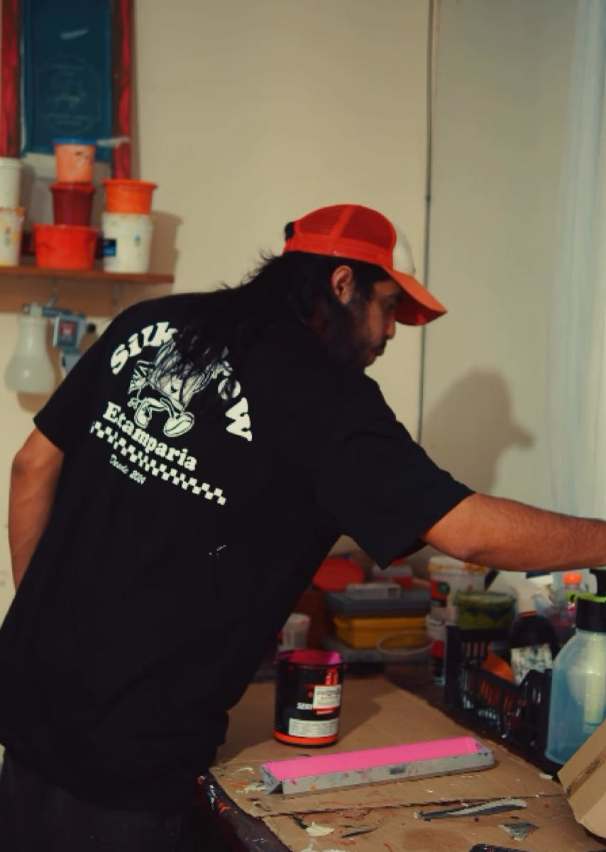 Estampador da Silk's Crew de costas no ateliê, com a camiseta da marca